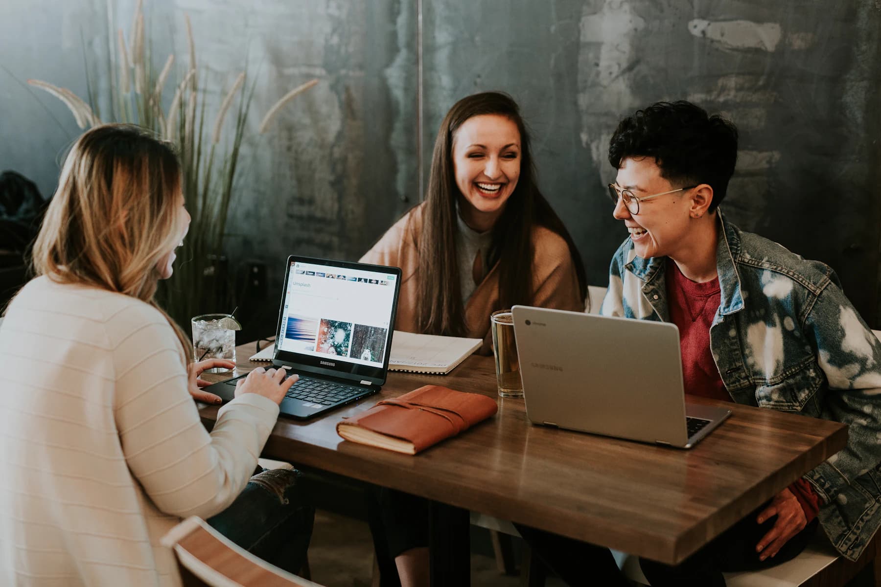 Pessoas trabalhando juntas e rindo em volta do notebook