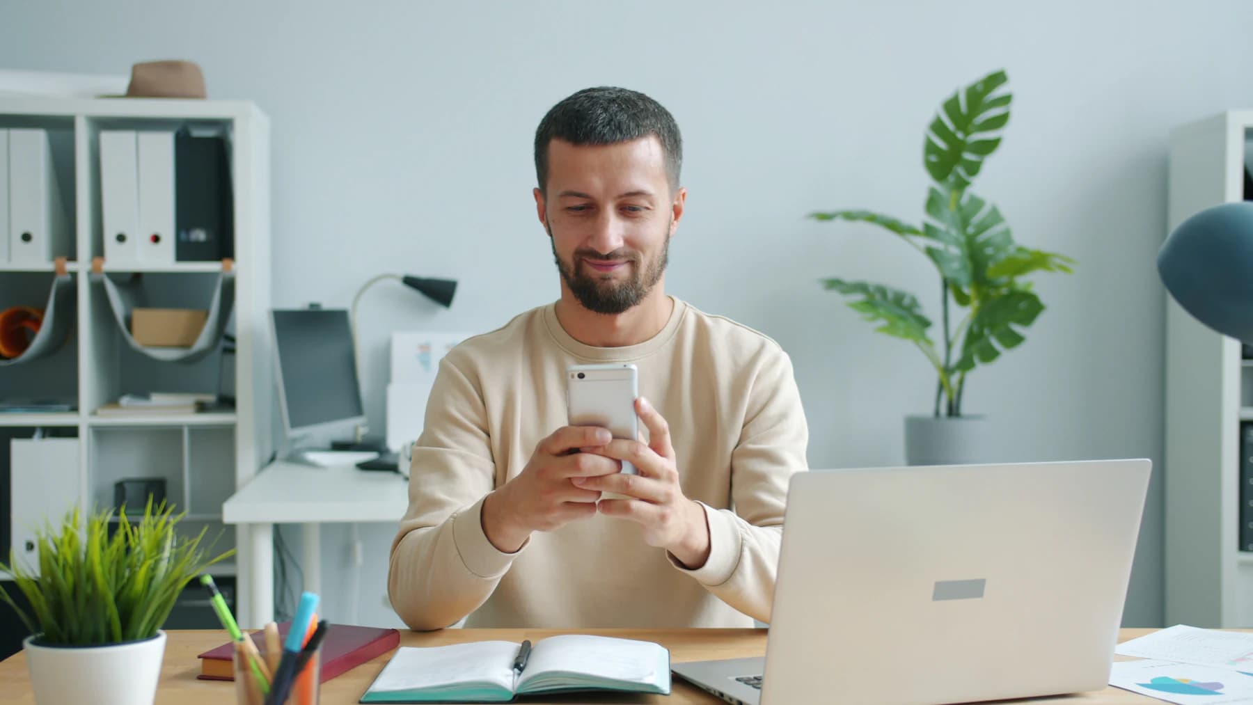 Homem sorrindo enquanto conversa pelo celular no escritório